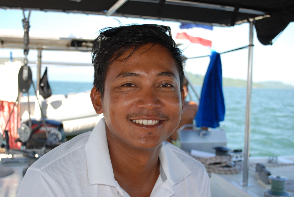 Man with brown hair and white polo shirt smiling.